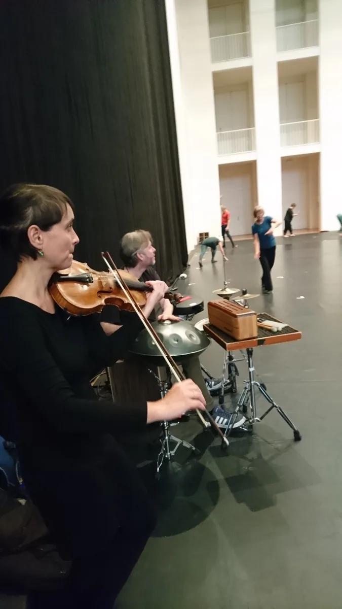 Zwei Musizierende liegen einander gegenüber auf dem Boden und spielen