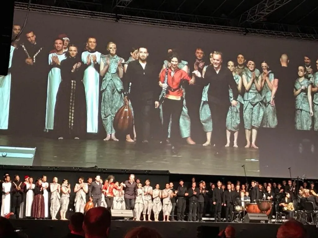 Großes Ensemble in weißen Gewändern auf einer Bühne in Leipzig