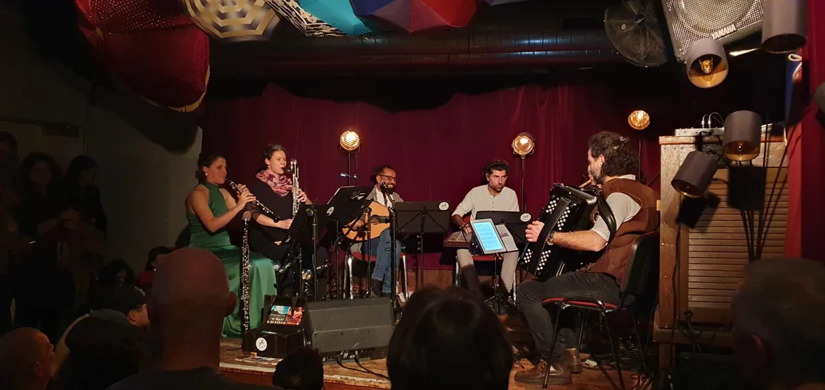Band im Konzert auf einer kleinen Bühne, Blick über das Publikum