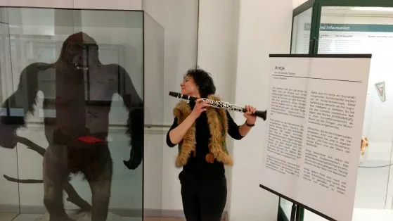 Eine Musikerin spielt Flöte vor einer Vitrine im Phyletischen Museum Jena