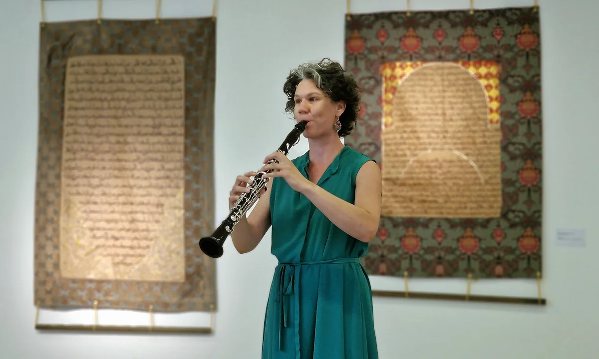 Antje Taubert spielt Klarinette zwischen zwei großen Kalligrafien bei der Vernissage „Mein Herz zittert wie Bambus“ in Gotha