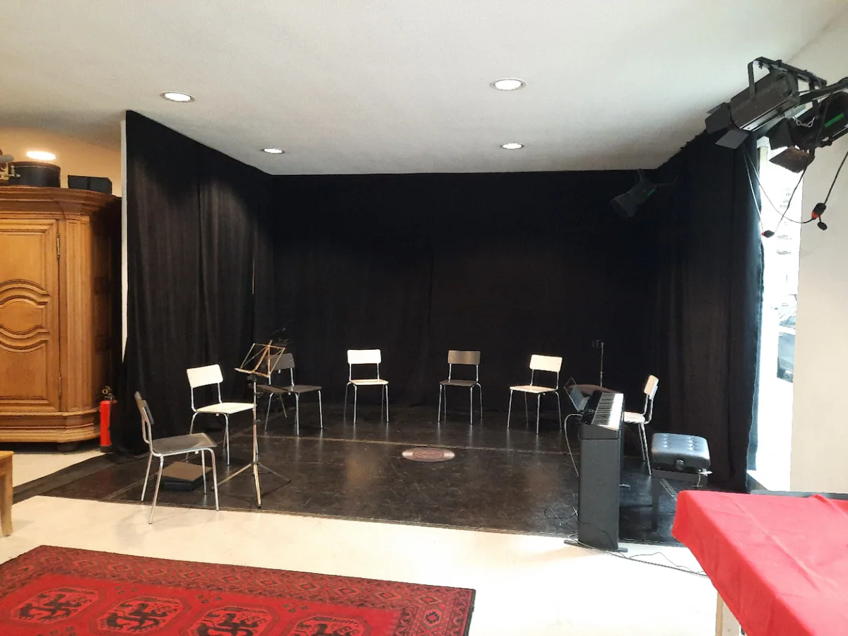 Der Saal im Puppentheater Jena: schwarze Vorhänge, ein Stuhlkreis und ein roter Teppich