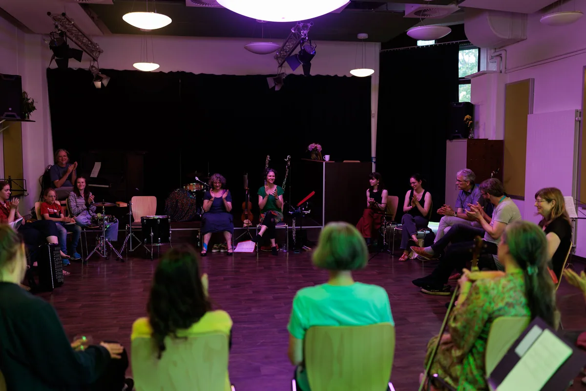 Blick von hinten durch den abgedunkelten Saal auf das musizierende Ensemble