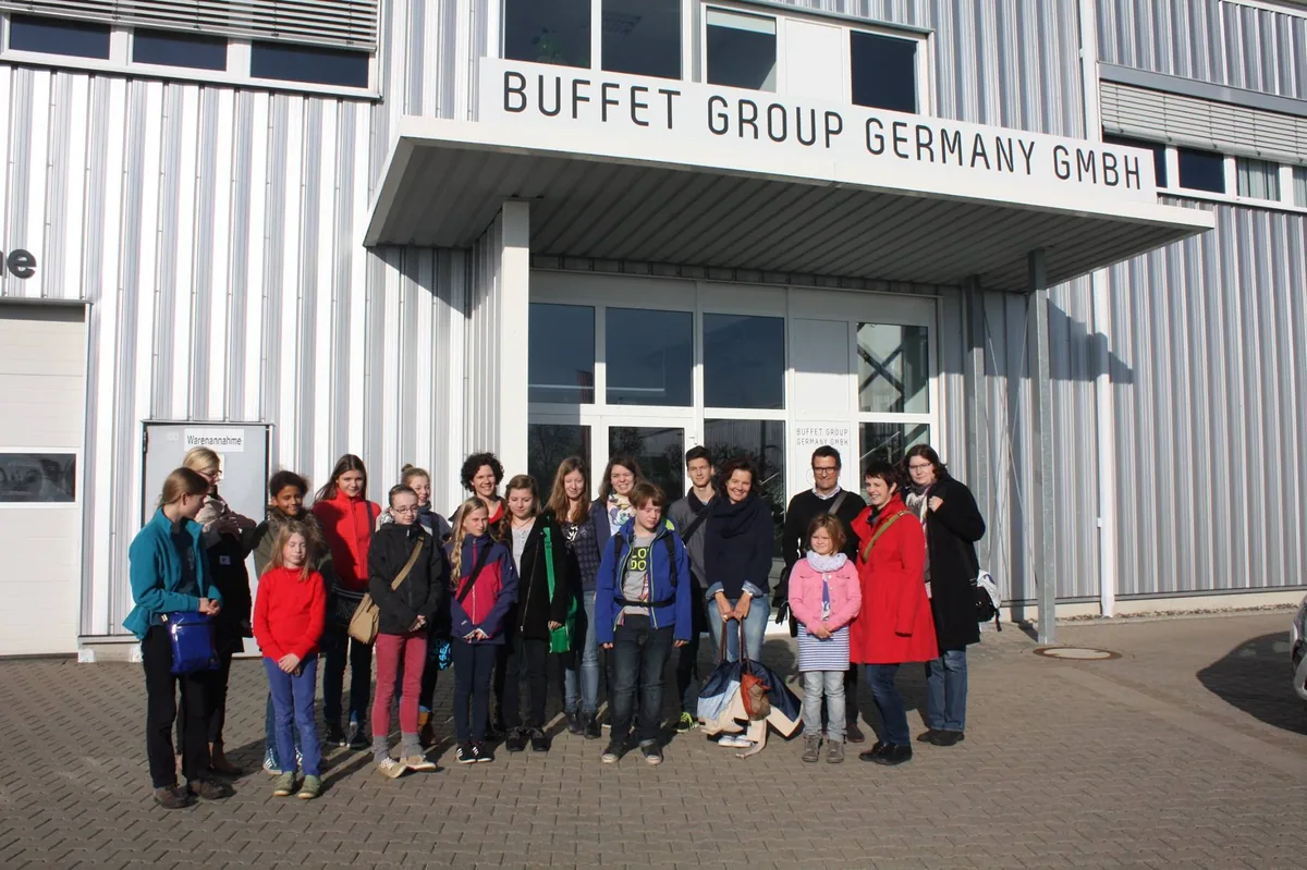 Schülergruppe vor dem Werksgebäude eines Instrumentenbauers