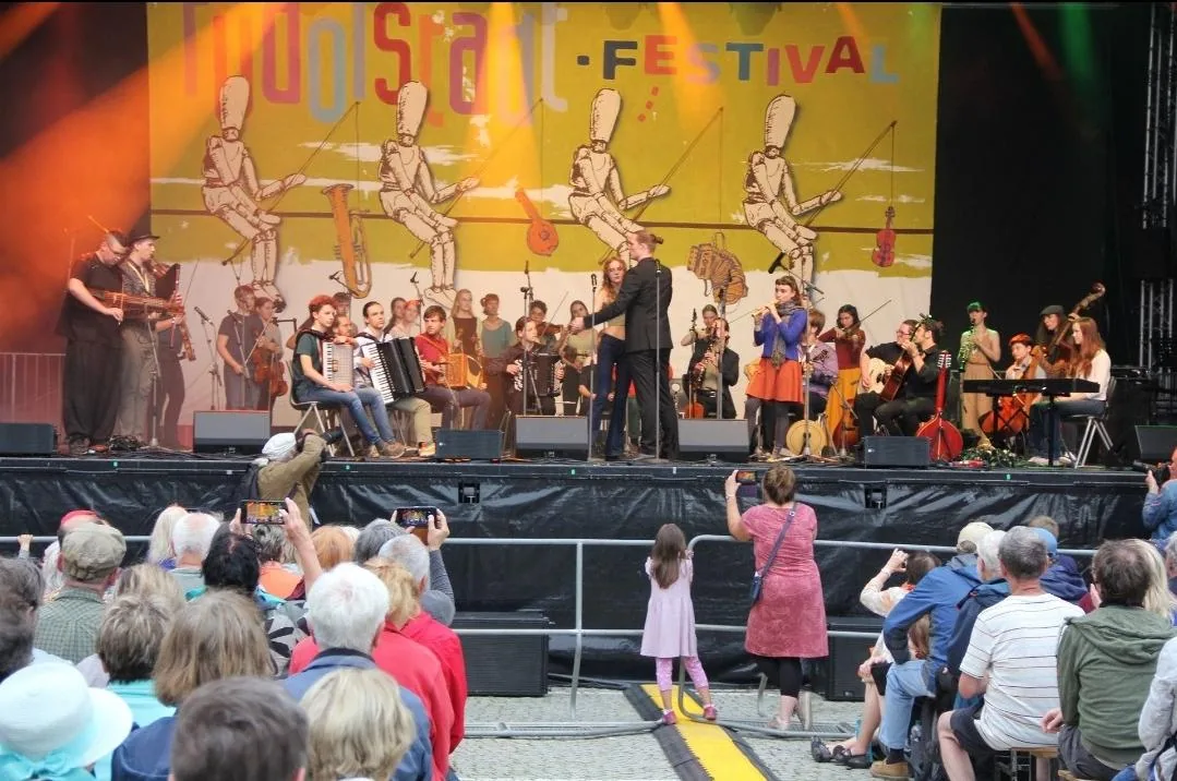 Jugendfolkorchester auf einer Festivalbühne vor vollem Platz