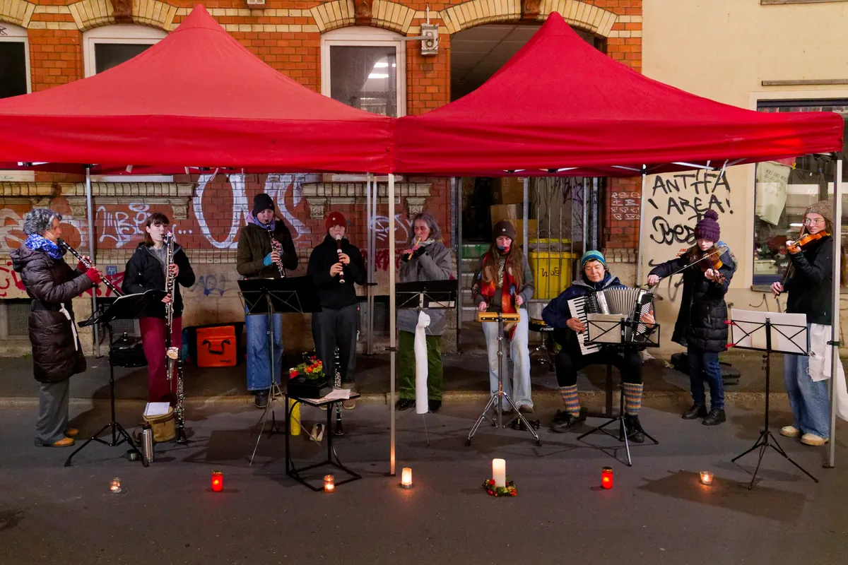 Das Klezmerensemble spielt abends unter roten Pavillons auf der Straße, vor den Notenpulten brennen Kerzen