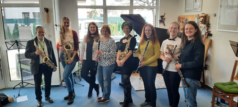 Gruppenfoto mit Saxophonen, Klarinetten und Querflöten in einem hellen Raum