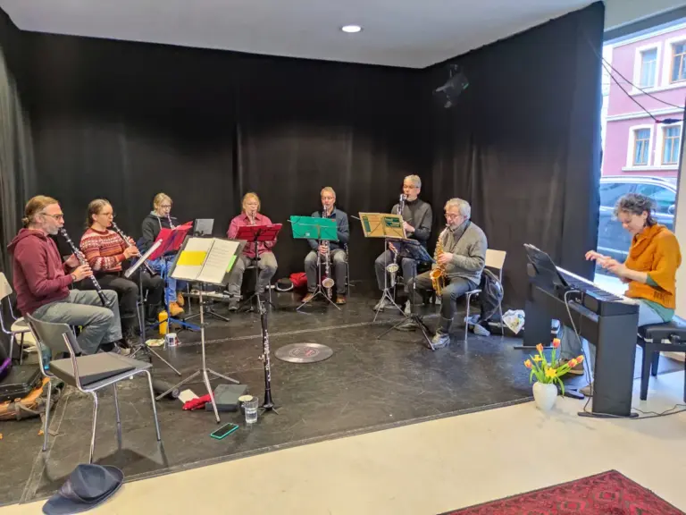 Kammermusik 2026 im Puppentheater: Klarinettistinnen und Klarinettisten im Halbkreis, am Flügel die Pianistin