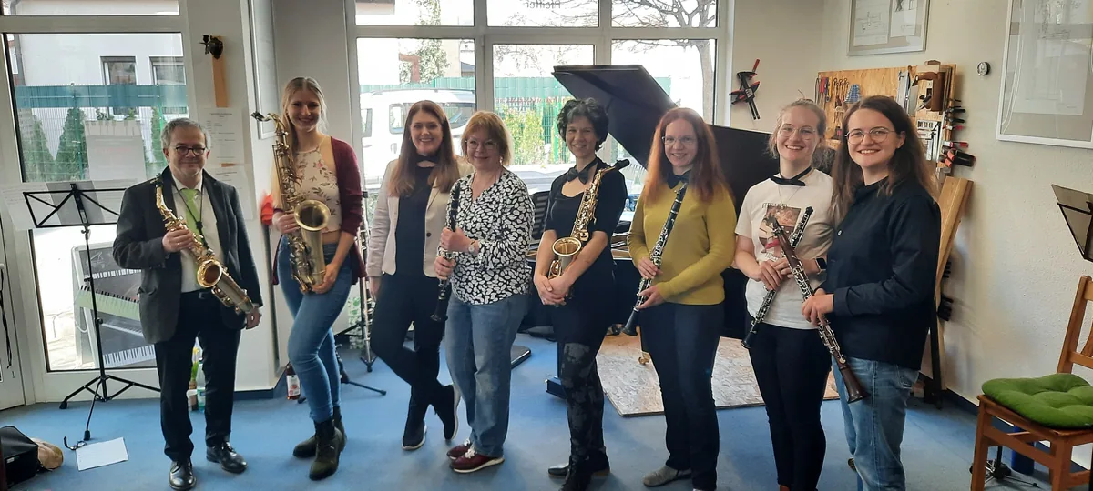 Gruppenfoto mit Saxophonen, Klarinetten und Querflöten in einem hellen Raum